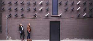 two women looking at wall of surveillance cameras